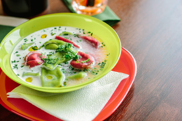 Green and red ravioli in soup for kids.