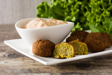 Falafel on a plate and tahini sauce on wooden table