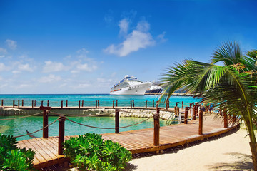 View from beach at tropical resort on cruise ships docked at port 