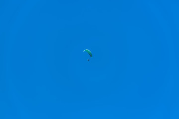 View of a paraglider hovering in the air, blue sky as background