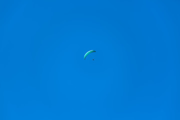 View of a paraglider hovering in the air, blue sky as background