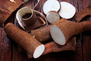 fresh cassava and peels and slices on rustic wooden table