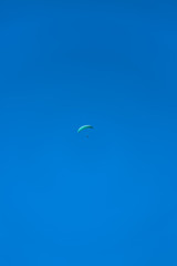 View of a paraglider hovering in the air, blue sky as background