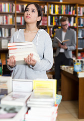 Positive student standing with pile of books