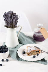 Home made cake with blueberries on white table with jar of blueberry confiture and lavender bouquet