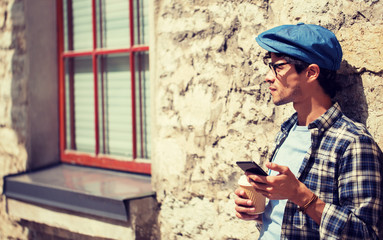 Fototapeta premium leisure, technology, communication and people concept - man with smartphone drinking coffee from disposable paper cup and texting message on city street