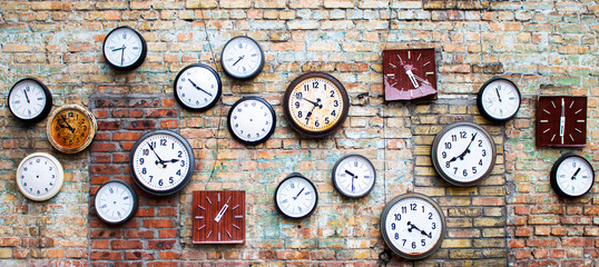 Collection of vintage clock hanging on an old brick wall - obrazy, fototapety, plakaty