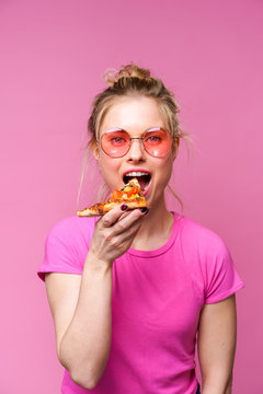 Image of blonde in pink t-shirt with piece of pizza in her hands