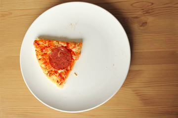 traditional Italian pizza with salami on a plate, one slice