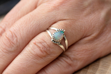 Silver ring with opal gemstone caboshon on female hand