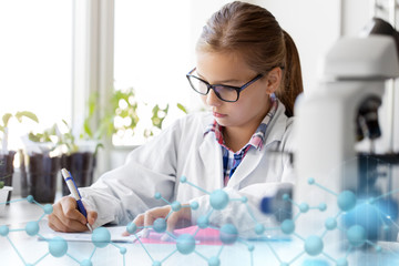 education, science and children concept - girl studying chemistry at school laboratory and writing...