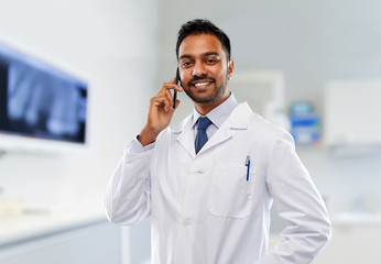 medicine, dentistry and healthcare concept - smiling indian male dentist in white coat calling on...
