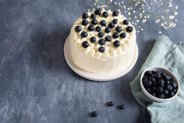 Homemade blueberry cake with cream cheese and fresh berrries on dark background. Copy space