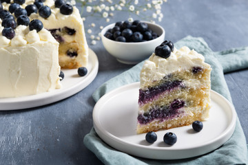 Piece of blueberry cake with cream cheese and fresh berrries on dark background. Close up