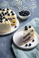 Piece of blueberry cake with cream cheese and fresh berrries on dark background. Copy space