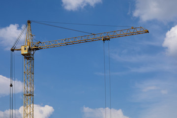 Industrial construction building crane against blue cloudy sky