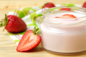 delicious strawberry yogurt in a jar and fresh ripe strawberries on a natural wooden table