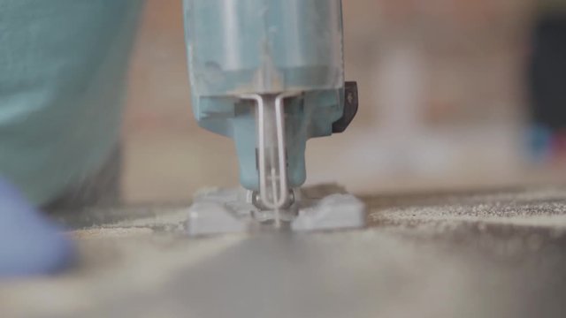 Electro jigsaw cutting a chipboard. Furniture manufacture. Concept of hand manufacturing. Craftman works in a workshop.