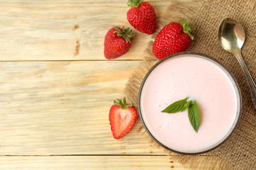 delicious strawberry yogurt in a jar and fresh ripe strawberries on a natural wooden table. top view