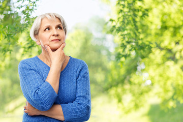 old people and decision making concept - portrait of senior woman in blue sweater thinking over...