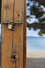 metal lock on a wooden textured board. on the background of the beach and the blue sea. concept - rest (vacation) is prohibited. closed for rest. no opportunity to rest