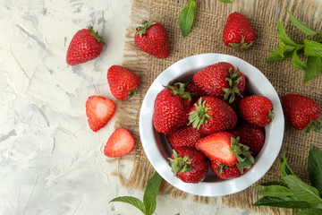 Ripe, delicious strawberries. Red strawberry in a ceramic bowl on a light concrete table. top view