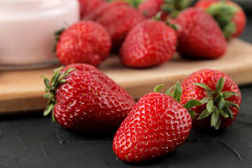 Ripe, delicious strawberries. Red strawberry berry closeup on a black concrete table.