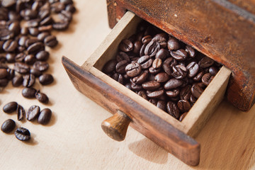 Freshly roasted coffee beans in the grinder on the wooden rustic board.