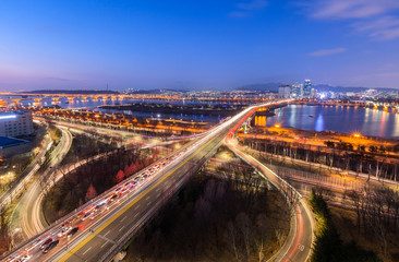 Cars passing in intersection, Han River and bridge at Night in Downtown Seoul, South Korea.