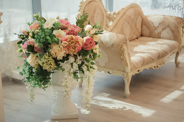 Flower wedding decorations . Beige sofa and floor vase with flowers classic interior