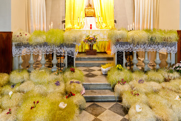 Alter in an italian church decorated with flowers for Easter holiday. Catholic church in Liguria region. Bright and yellow flowers.