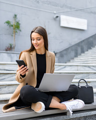 Beautiful young woman wearing autumn coat using laptop