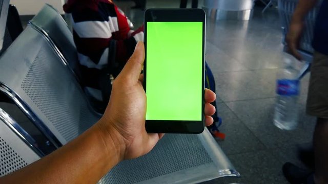 Close up hand holding using mobile smart phone green screen in community mall, shopping center. Royalty high quality free stock video footage of holding a smartphone green screen display in the hand