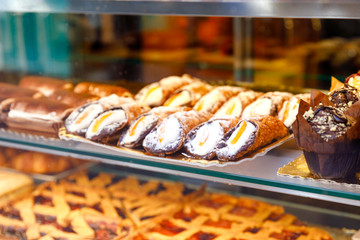 Sweet homemade cannoli stuffed with ricotta cheese cream and pistachial Sicilian dessert at market in Italy