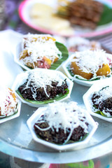 Thai sweet dessert Glutinous rice with coconut toppings on banana leaves.