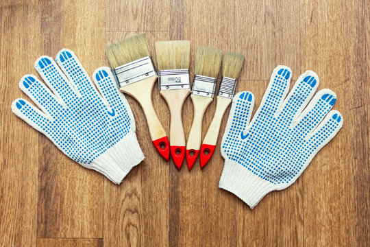 Composition from painting tools with paint brushes, gloves and paint roller on the wooden background