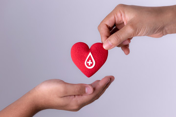 Woman hand gives a red heart to a boy hand for blood donation concept,World blood donor day. Copy...