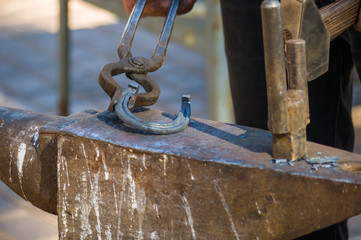 blacksmith performs the forging of hot glowing horseshoe on the anvil