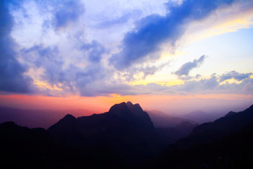 Sunset in sky and cloud, beautiful colorful twilight time with silhouette of mountain.