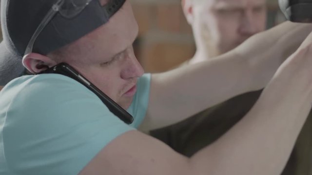 Close up of the carpenter talking by cellphone by doing his work. Concept of hand manufacturing. Furniture producing. Failure to comply with safety standards.