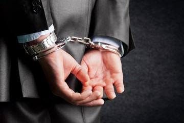 Cropped image of male hands in handcuffs behind his back