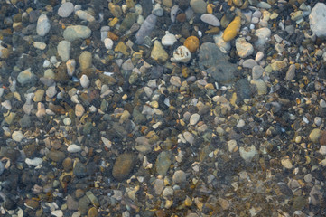 pebble stones on the sea beach, the rolling waves of the sea with foam