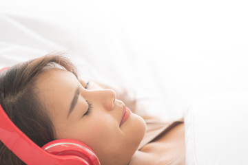 Young beauty asian woman sleep with little smile and listening music from headphone in modern bedroom, Relax and clam in the morning, Copy space on top right, Summer holiday