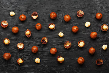 Fototapeta na wymiar Purified and shell repeats macadamia nuts on black textural stone background. Healthy eating concept