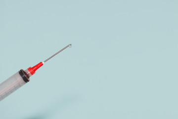 Syringe closeup isolated on blue background with drop, High resolution, Top view with copy space, Medical concept