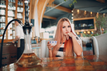 Young pretty girl drinks hot coffee in cafe.