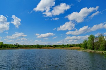 Obraz na płótnie Canvas Spring rural landscape, pond and sky, clouds.