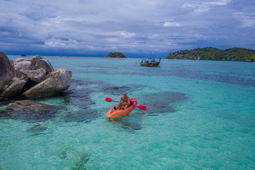 Aerial drone view of man kayaking in crystal clear lagoon sea water during summer day near Koh Kra island in Thailand. Travel tropical island holiday concept