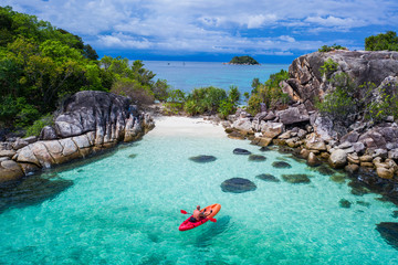 Aerial drone view of man kayaking in crystal clear lagoon sea water during summer day near Koh Kra island in Thailand. Travel tropical island holiday concept - obrazy, fototapety, plakaty