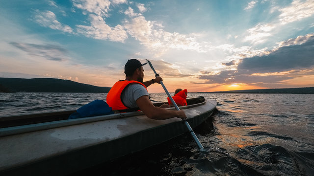 Father and a son go kayaking in the sunset
